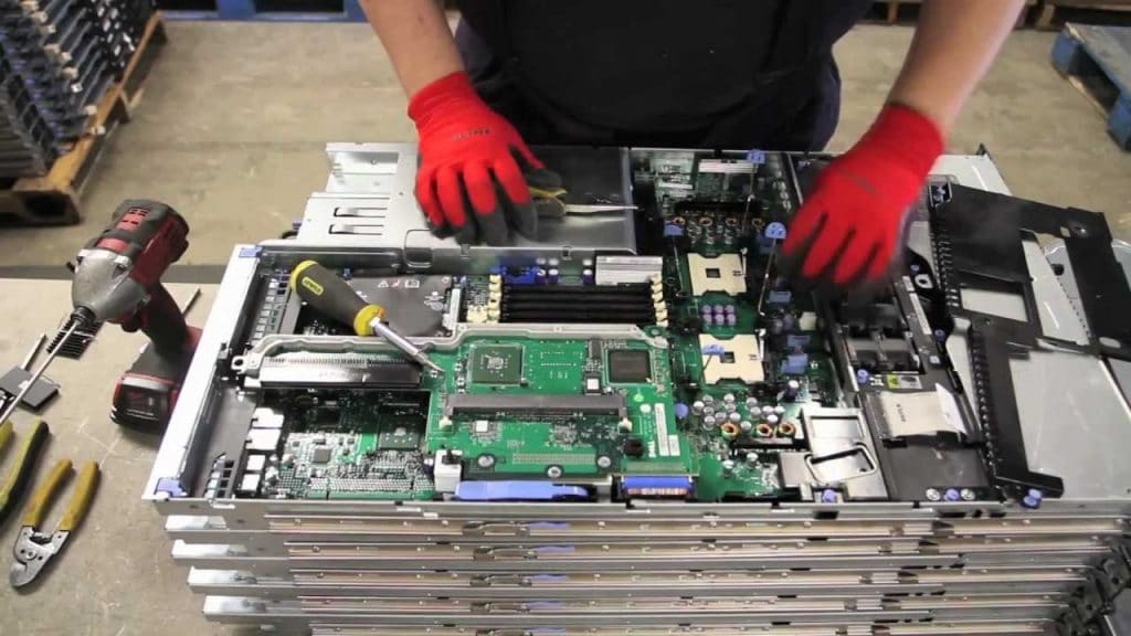 A technician assembling a server with tools on a workbench.